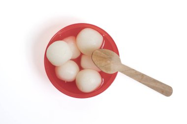 Geleneksel Hint tatlısı Rasgulla beyaz arka planda tahta kaşıkla kırmızı bir kasede servis yapıyordu..