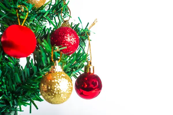 Kırmızı ve altın takılarla süslenmiş bir Noel ağacı dalının beyaz arka planda yakın plan görüntüsü. Tatil dekorasyonu, mevsimlik tebrik kartları ve şenlikli tasarımlar için ideal..