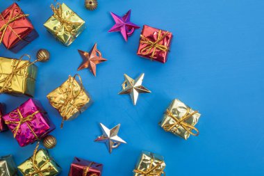 Renkli hediye kutuları ve parlak mavi bir arka planda dizilmiş süs yıldızları. Bayram ve kutlama kartları için mükemmel..