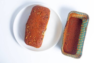 A freshly baked walnut cake served on a plate, with an empty paper box beside it, set against a clean white background. perfect for bakery promotions, and food photography. clipart