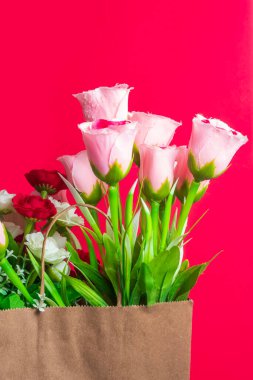 Kese kağıdında pembe, kırmızı ve beyaz çiçekler bulunan renkli bir buket yapay çiçek. Dekorasyon, hediye verme ya da romantik gösteriler için mükemmel..