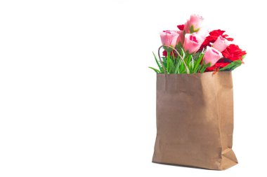 Kahverengi bir kesekağıdında sergilenen canlı pembe ve kırmızı çiçek koleksiyonu, çevreci dostluğu ve doğal güzelliği simgeliyor..