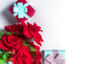 Zarif hediye kutularının ve beyaz arka planda kırmızı güllerin üst görüntüsü. Aşkı, özel durumları ya da minnettarlığı kutlamak için mükemmel..