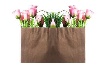 Tazelik ve mutluluğu sembolize eden pembe gül çiçekleriyle dolu kahverengi bir kese kağıdı..