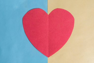 The red paper heart centered on a background divided into blue and yellow parts. Represents love, clipart