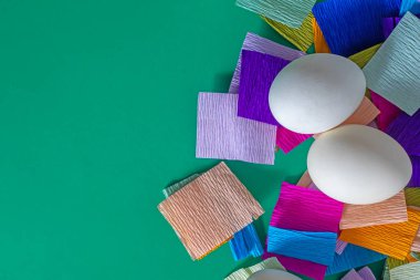 Top view of white eggs with colored paper on a green background. Happy Easter. clipart