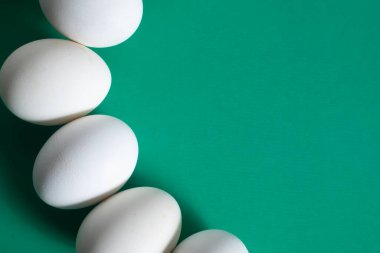 Beyaz yumurtalar temiz yeşil bir yüzey üzerinde metin için kopyalama alanı ile ustalıkla düzenlenmiştir..