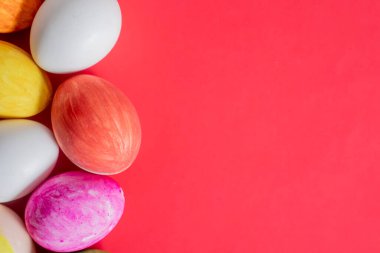 Canlı kırmızı arka planda parlak renkli Paskalya yumurtaları. Mevsimlik ya da tatil kutlamaları için mükemmel..