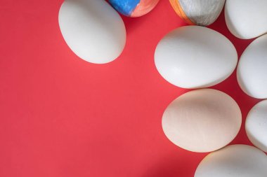 Easter eggs of various colors, including plain white and beautifully painted ones, are set against a vibrant red background. clipart