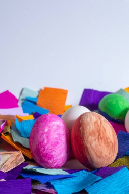 White and colored Easter eggs with vibrant crepe paper on a white background, symbolizing holiday decoration and festivity. clipart