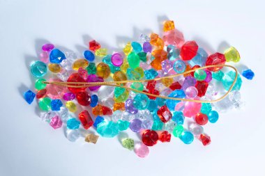 Çeşitli renkli dekoratif mücevherlerin üzerinde altın bir zincir. El işi, dekorasyon ve yaratıcı tasarımlar için mükemmel..