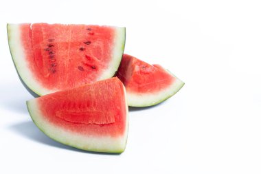 Sulu karpuz dilimleri temiz beyaz bir zemin üzerine kurulmuş canlı kırmızı derileri, yeşil derileri ve siyah tohumlarıyla hava atıyorlar..