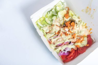 Taze sebzeli salata, salatalık, domates ve marul içeren küçük bir kapta serpiştirilmiş kremalı sosun yakın plan görüntüsü..