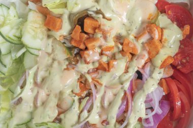Taze sebze salatasını marul, domates, salatalık, soğan, kremalı sos ve lezzetli ve sağlıklı bir yemek seçeneği için çıtır çıtır sosla kaplayın..