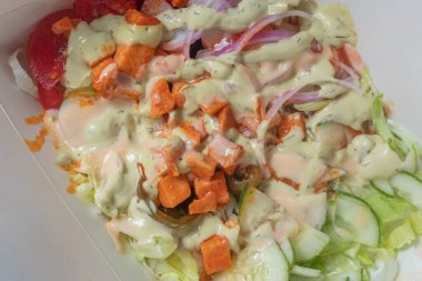 Domates, salatalık ve ıspanak gibi renkli sebzeler kremalı bir sosla kaplanarak sağlıklı bir yemek için mükemmel bir salata sunuluyor..