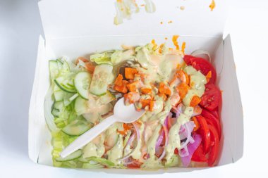 Salatalı, salatalıklı, domatesli renkli bir sebze salatası. Paket paketinde servis ediliyor, sosla kaplanıyor ve uygun olması için kaşıkla servis ediliyor ve sağlıklı bir yemek veriliyor..