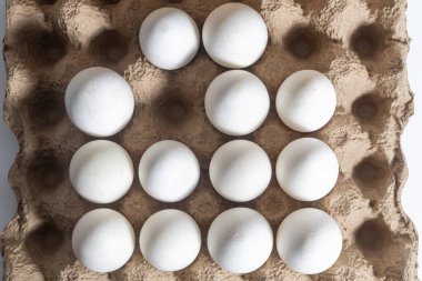 Yukarıdan bakıldığında, ızgara şeklinde düzenlenmiş 12 beyaz yumurta içeren bir karton. Yemek, yemek ya da yumurta konsepti için mükemmel..