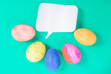 Canlı yeşil bir yüzeye yerleştirilmiş boş bir konuşma balonunu çevreleyen parlak boyanmış yumurtalar Paskalya gibi kavramlar için mükemmeldir..