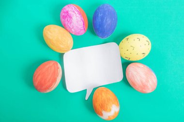 Paskalya yumurtaları boş bir konuşma baloncuğunun etrafına dizilmiş, parlak yeşil bir zemin üzerine kurulmuş, mevsimsel ve şenlikli tasarım amaçları için mükemmel..