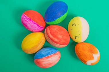 Canlı Paskalya yumurtaları çeşitli renkler ve parlak yeşil bir yüzey üzerinde neşeli bir tasarım, tatil heyecanını, yaratıcılığı ve şenlikli kutlamaları sembolize ediyor..