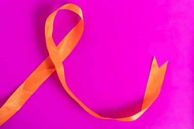 Turuncu bir kurdelenin parlak bir görüntüsü. Kalın pembe bir arka plan. Sebepleri ve desteği temsil ediyor. Kampanyalar için mükemmel farkındalık ve birlik çabalarını desteklemek için..
