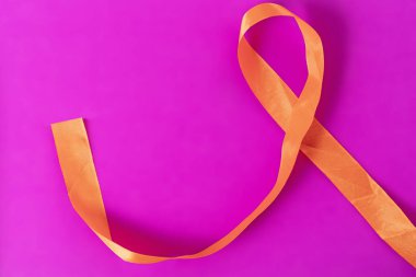 Turuncu bir kurdele, farkındalık temalarını temsil eden canlı pembe bir arka planda güzelce kıvrılır. Kampanyalar ya da dekoratif tasarımlar için mükemmel.