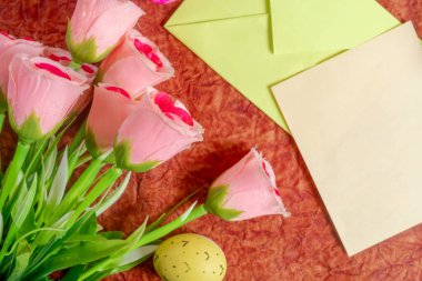 Pembe güller, desenli bir yüzey ve renkli zarflar kutlama ve yaratıcılığı çağrıştırıyor..