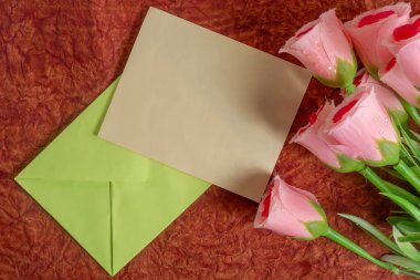 Pembe güller ve boş bir zarf duygularını ifade etmek için mükemmel bir ortam yaratır..