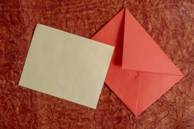 Düz bir tasarım, düz kahverengi bir kart ve kırmızı bir yüzey üzerinde canlı kırmızı bir zarf. Yazışma, hediye verme ya da etkinlik daveti gibi kavramlar için mükemmel.