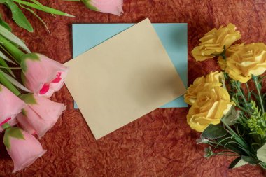 Pembe ve sarı çiçeklerle çevrili desenli bir yüzeye yerleştirilmiş boş bir kart çeşitli durumlar için neşeli ve davetkar bir ışık sağlar..