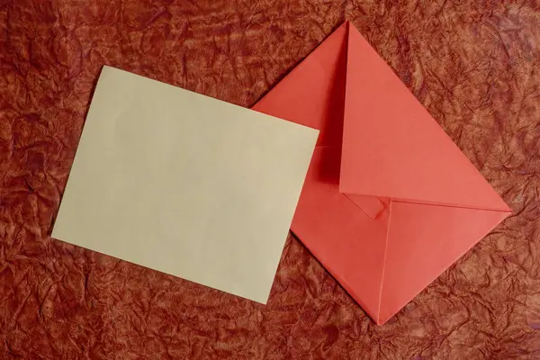 Düz bir tasarım, düz kahverengi bir kart ve kırmızı bir yüzey üzerinde canlı kırmızı bir zarf. Yazışma, hediye verme ya da etkinlik daveti gibi kavramlar için mükemmel.