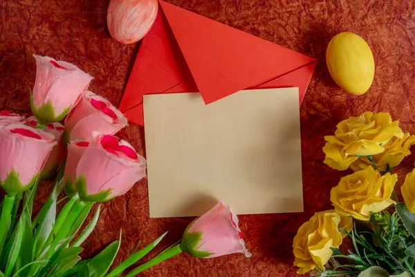 Renkli buket, kırmızı zarf ve arkaplandaki paskalya yumurtaları. Bayram kutlamaları ve bahar davetiyeleri için mükemmel..