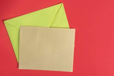 Yeşil bir zarf ve parlak kırmızı bir arka plan üzerine kurulmuş kahverengi bir kart. İletişim, yaratıcılık ve kutlama temaları için mükemmel.