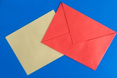 Mavi arka planda kahverengi kağıtlı kırmızı bir zarfın canlı bir görüntüsü. İletişim, yazışma ve mesajlaşma için uygun.