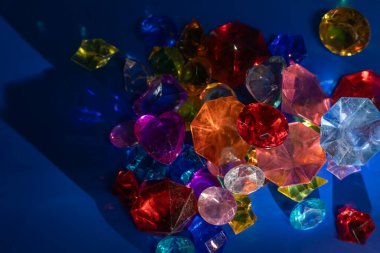 Parlak renkli değerli taşlar ve kristaller yoğun mavi bir yüzeyde ışık altında sergilenir. Bu da renkleri ve berraklığı ortaya çıkarır..