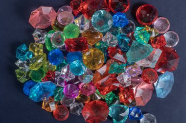 Çok renkli değerli taşlar ve cam kristallerden oluşan çarpıcı bir düzenleme canlı renkler sergiliyor ve koyu arkaplana karşı parıldayan tasarımlar sergiliyor..