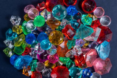 Değişik şekil ve boyutlarda çok renkli taşlardan oluşan canlı bir düzenleme, zıt bir karanlık yüzeye karşı parlak bir şekilde parıldıyor..