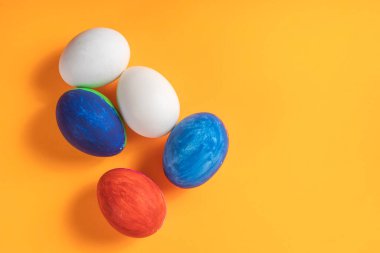 Parlak ve renkli yumurta renkleri canlı turuncu bir yüzey üzerinde sergilenir. Paskalya ve bahar temaları için mükemmeldir..