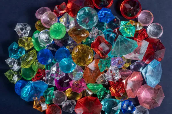 Değişik şekil ve boyutlarda çok renkli taşlardan oluşan canlı bir düzenleme, zıt bir karanlık yüzeye karşı parlak bir şekilde parıldıyor..