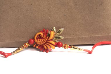 Kırmızı iplik ve altın aksanlı zarif bir şekilde tasarlanmış rakhi, Raksha Bandhan 'ın şenlikli kutlamasını simgeliyor..