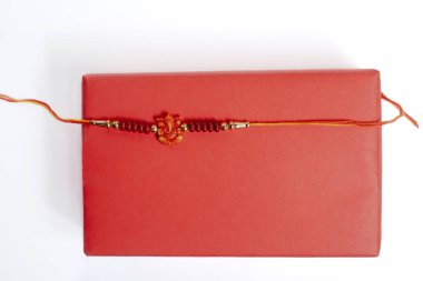 Canlı kırmızı bir hediye kutusu. Hassas boncuklu bir bilezik. Kapağında turuncu bir iplikle bağlanmış. Raksha Bandhan için mükemmel bir hediye..