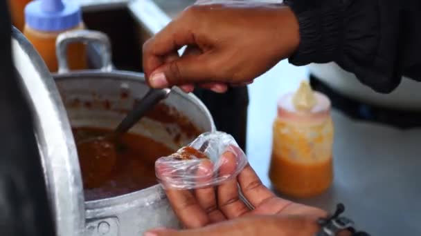 インドネシアの男性ストリートフードベンダーは 屋外市場で顧客にサービスを提供しています タラカンの通りで客に バタゴール一閑 という料理を作る男 — ストック動画