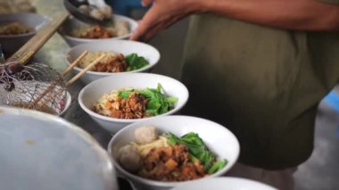 Tavuklu erişte hazırlıyorum. Penjual mie ayam bakso ya da alıcıya tavuklu erişte yapan köfteli tavuklu erişte satıcısı manzarası. Seçici odak. 