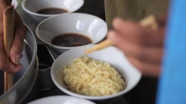 Tavuklu erişte hazırlıyorum. Penjual mie ayam bakso ya da alıcıya tavuklu erişte yapan köfteli tavuklu erişte satıcısı manzarası. Seçici odak. 