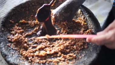 Rujak petisi hazırlamak. Rujak petisi, Java 'nın buharda pişirilmiş sebzelerden, kızarmış sarımsak, acı biber, petis (mayalanmış karides ezmesi) ve yer fıstığından yapılan geleneksel yemektir.