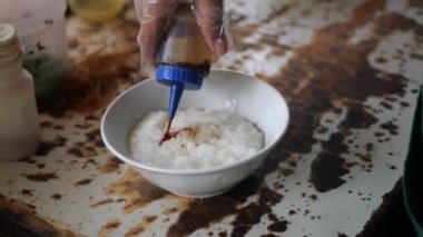 Tavuk lapası satıcısı ya da tukang bubur ayam müşteriler ya da pelangganlar için yemeğini hazırlar. Bubur Ayam (Tavuk Lapası), Malezya Geleneksel Yemeği tuzlu yumurtalı beyaz pirinç lapasından oluşur, 