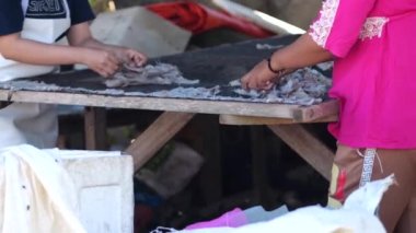 Endonezyalı işçiler güneşte kurutulmak üzere balık düzenliyor, ince tuzlanmış balıklara dönüştürülüyor.