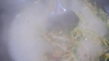 Şefin tavada yaptığı acılı sebze ve kızarmış etle Aceh eriştesi pişirmek. Yemek tarifi konseptini kapat.