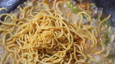 Şefin tavada yaptığı acılı sebze ve kızarmış etle Aceh eriştesi pişirmek. Yemek tarifi konseptini kapat.