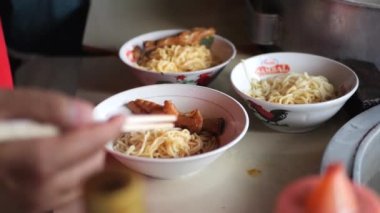 Tavuklu erişte hazırlıyorum. Penjual mie ayam bakso ya da alıcıya tavuklu erişte yapan köfteli tavuklu erişte satıcısı manzarası. Seçici odak. 